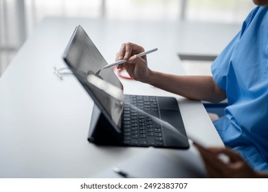 A woman is using a tablet with a pen on it. She is wearing a blue shirt. The tablet is open to a page with a picture of a person - Powered by Shutterstock