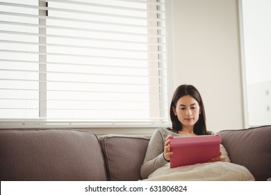 Woman using tablet while sitting on sofa at home