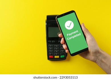 Woman using terminal for contactless payment with smartphone on yellow background, top view. Transaction completed screen on device - Powered by Shutterstock