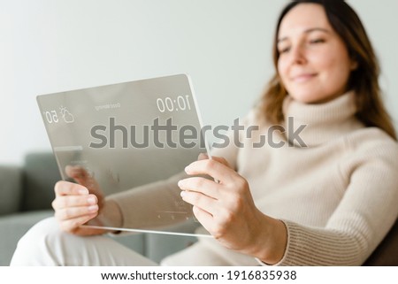 Woman using transparent tablet on a couch innovative technology