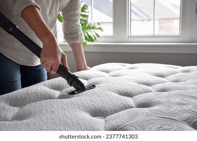 Mujer usando aspiradora para aspirar colchón en un dormitorio