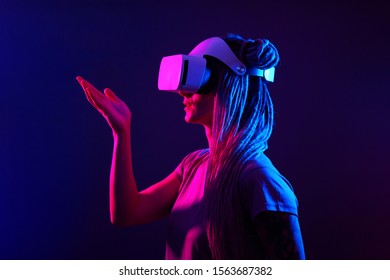 Woman is using virtual reality headset. Neon light studio portrait.