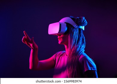 Woman is using virtual reality headset. Neon light studio portrait.