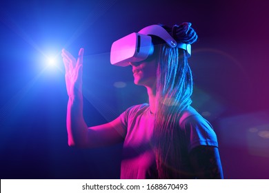 Woman is using virtual reality headset. Neon light studio portrait. Concept of virtual reality, simulation, gaming and future technology.
