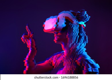 Woman is using virtual reality headset. Neon light studio portrait. Concept of virtual reality, simulation, gaming and future technology. Image with glitch effect.