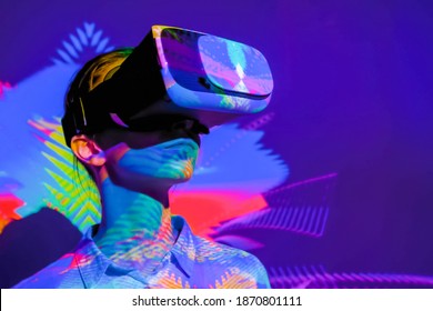 Woman using virtual reality headset, looking around at interactive technology exhibition with multicolor projector light illumination. VR, augmented reality, immersive, entertainment concept - Shutterstock ID 1870801111