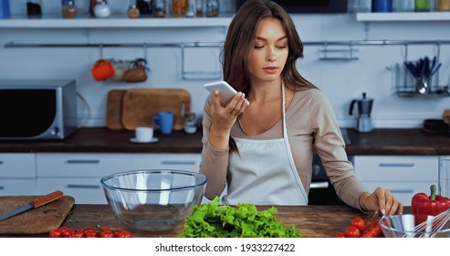 Woman Using Voice Assistant While Holding Smartphone Near Ingredients