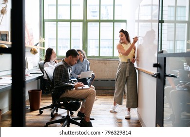 Woman using whiteboard in a small team meeting - Powered by Shutterstock