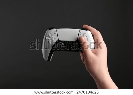 Woman using wireless game controller on dark background, closeup
