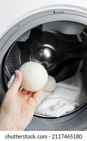 Woman Using Wool Dryer Balls For More Soft Clothes While Tumble Drying In Washing Machine Concept. Discharge Static Electricity And Shorten Drying Time, Save Energy.