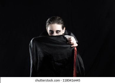 Woman in a vampire costume for halloween. Studio shot of a young female dressed up in Dracula costume on black background