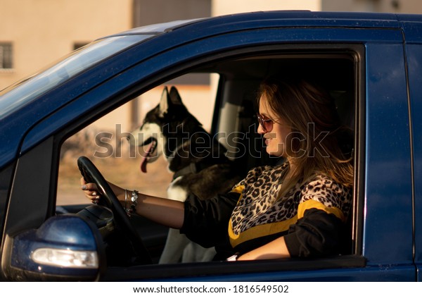 Woman in\
vehicle interior with her Siberian Husky\
dog.