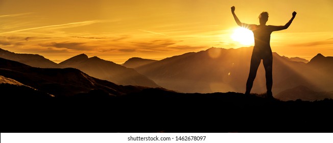 Woman in victory pose at sunrise on a mountain peak Silhouette - Powered by Shutterstock