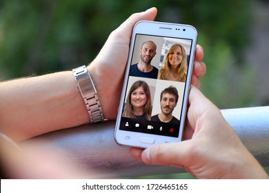 Woman in video conference with a group of people. Young woman having a video chat with many people on her mobile phone. Woman in her home with smartphone in her hands.