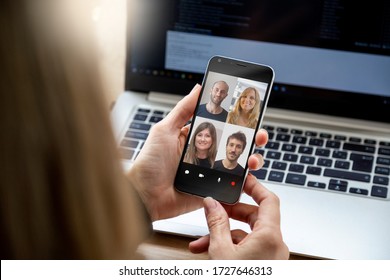 Woman In Video Conference With A Group Of People. Young Business Woman Having A Video Chat With Coworkers On Her Mobile Phone. Woman In Her Workplace With Smartphone In Her Hands.