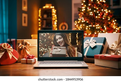 Woman videocalling on a laptop and giving a Christmas gift, Christmas at home concept - Powered by Shutterstock