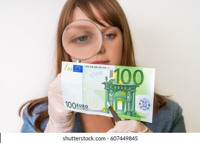 Woman Viewing Counterfeit Euro Banknote With Magnifying Glass