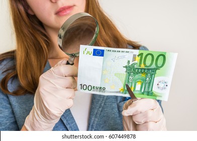 Woman Viewing Counterfeit Euro Banknote With Magnifying Glass