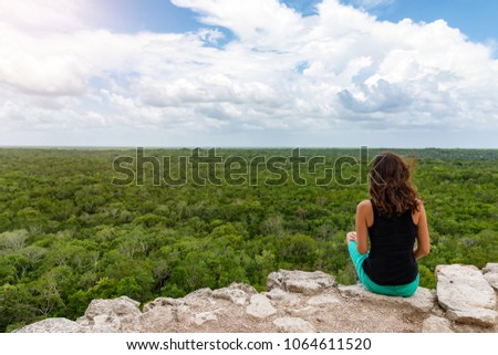 Woman views over the rain forest of Yucatan, Mexico, from the top of the Nohoch Mul pyramid in Coba