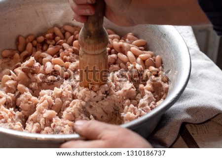 Woman in village cooking beans, soybeans, simple rustic food. Beans, soybeans prepared in aluminum bowl. Vegetarian healthy food concept.