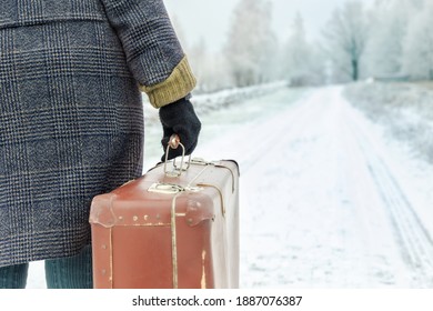 Woman with vintage suitcase walking on road in winter

