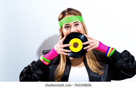 Woman with a vinyl record in 1980's fashion on a white background