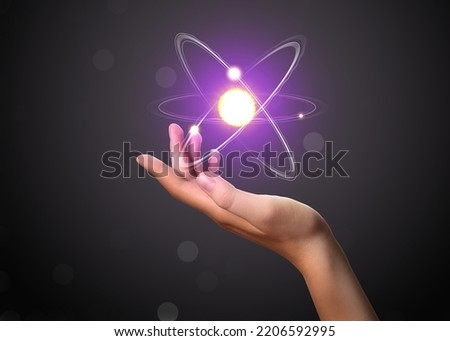 Woman and virtual model of atom on dark background, closeup