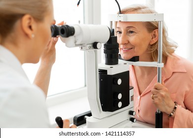 Woman Visiting Ophthalmologist. Pleasant Short-haired Woman With Blue Eyes Having Her Eyes Checked In Binocular Apparatus