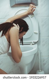 Woman vomits in to the toilet in the bathroom. Young woman vomiting into the toilet bowl in the early stages of pregnancy or after a night of partying and drinking.
