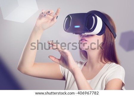 Woman in VR headset looking up and trying to touch objects in virtual reality. VR is a computer technology that simulates a physical presence and allows the user to interact with environment.