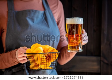 woman waiter holds beer and chips 