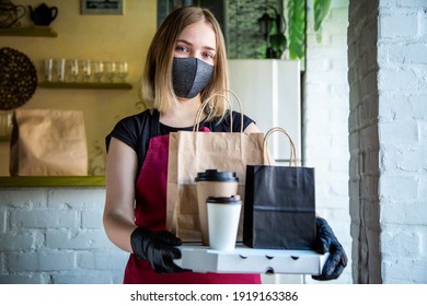 Woman Waiter In Protective Medical Mask And Gloves Work With Takeaway Orders. Waiter Giving Takeout Meal While City Covid 19 Lockdown, Coronavirus Shutdown. Food Pizza Coffee Delivery.