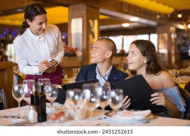 Woman waiter is taking order from clients in restaurante indoor - Powered by Shutterstock