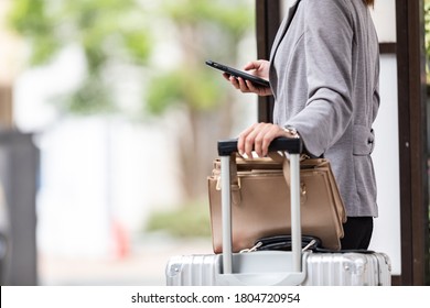 Woman waiting for the bus with a suitcase at the bus stop
