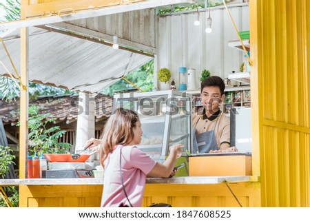 woman waiting for grilled sausage food which is being prepared by the man