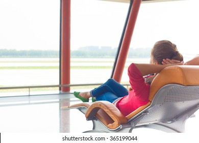 Woman Waiting For Her Flight At The Airport On Lounge Chair