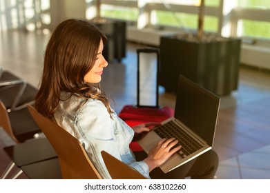 Woman waiting his flight at airport terminal, sitting on chair and typing on the laptop  - Shutterstock ID 638102260