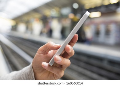 Woman Waiting On Subway Platform With Her Cell Phone 