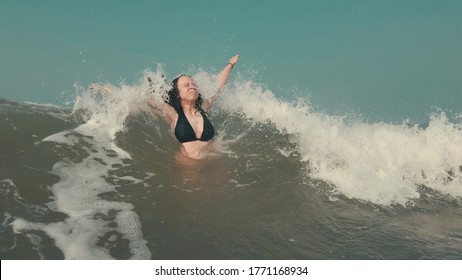 Frauen warten auf Meereswelle. Seitliche Sicht auf nasses Weibchen schwimmen im Meerwasser und warten auf schneebedeckte Welle, während Sie sich auf der Ferienanlage sonnigen Tag erholen
