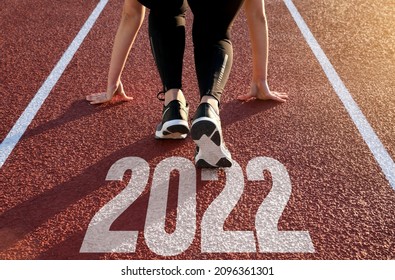 A woman waiting to start on an athletics track with the year 2022 engraved on the floor