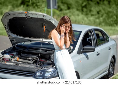 A Woman Waits For Assistance Near Her Car Broken Down On The Road Side.