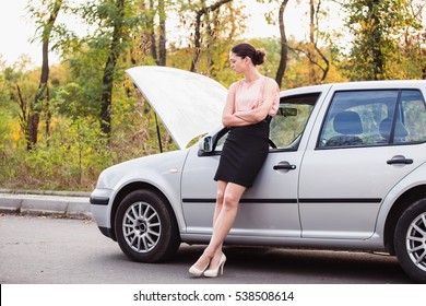 A Woman Waits For Assistance Near Her Car Broken Down On The Road Side 