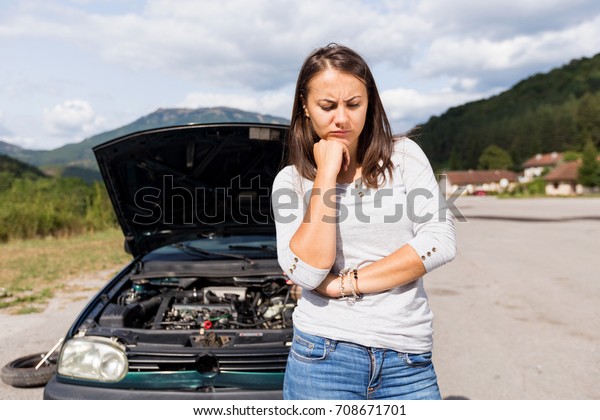 Woman waits\
for assistance near her car broken\
down