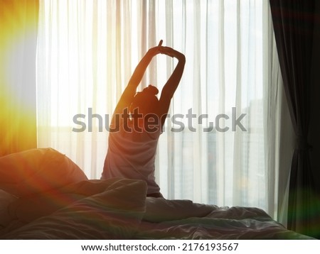 woman waking up in the morning, the sun shines on her from the big window.