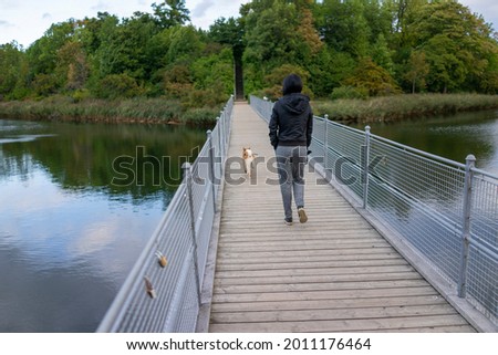 a woman walked with the dog in the park with the lake.