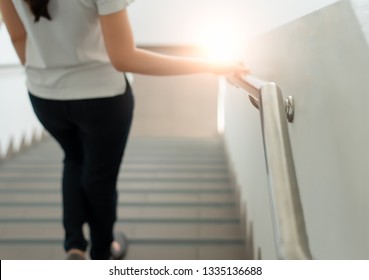 The woman walked, holding the railing, walking up and down the building for safety in balance during the steps up and down the stairs. In order to prevent accidents that may occur when being alone. 