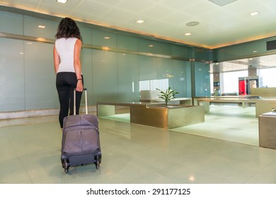 Woman Walking In The Airport With Her Trolley.