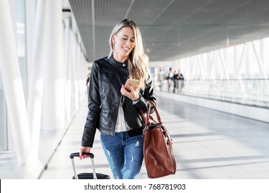 Woman Walking In Airport And Looking At Mobile Phone