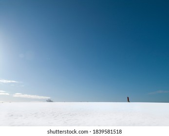 A Woman Walking Alone In A Snow-covered On Cold And Sunny Winter Day With The Background Of A Clear, Blue Sky.