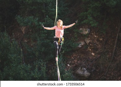 A woman is walking along a stretched sling over a forest, Highliner balances over the abyss, Highline in Turkey, Purposeful girl goes to the goal. - Powered by Shutterstock